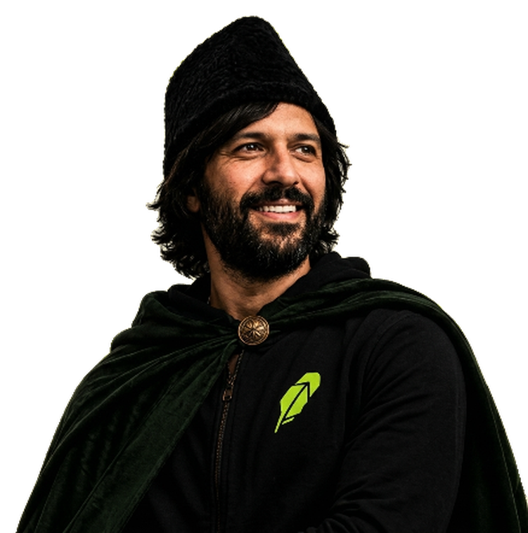 Baiju in a black knit cap and green cloak over a hoodie, smiling